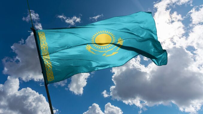 The flag of Kazakhstan mounted on a pole, fluttering in the wind.
